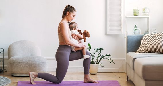 Maman qui fait du yoga avec son bébé dans les bras
